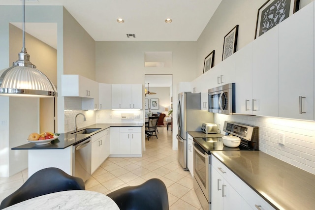 kitchen with pendant lighting, sink, light tile patterned floors, white cabinetry, and stainless steel appliances