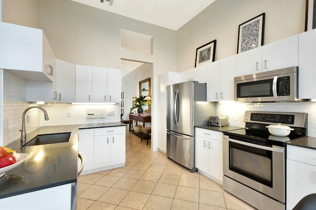 kitchen with white cabinets, stainless steel appliances, light tile patterned flooring, and sink