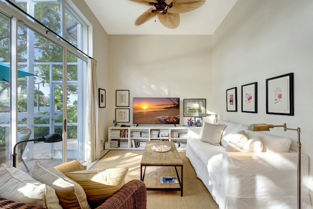 living room with ceiling fan, light colored carpet, a towering ceiling, and a wealth of natural light