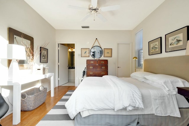 bedroom featuring ceiling fan, light hardwood / wood-style flooring, and ensuite bath