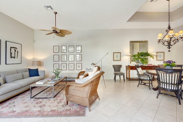 tiled living room with a tray ceiling and ceiling fan with notable chandelier