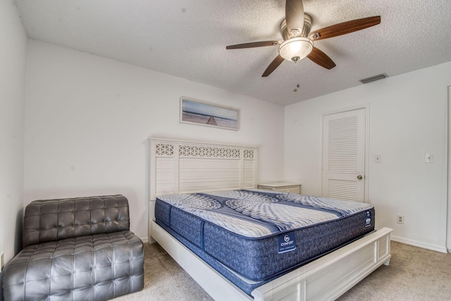 bedroom featuring carpet flooring, ceiling fan, a closet, and a textured ceiling