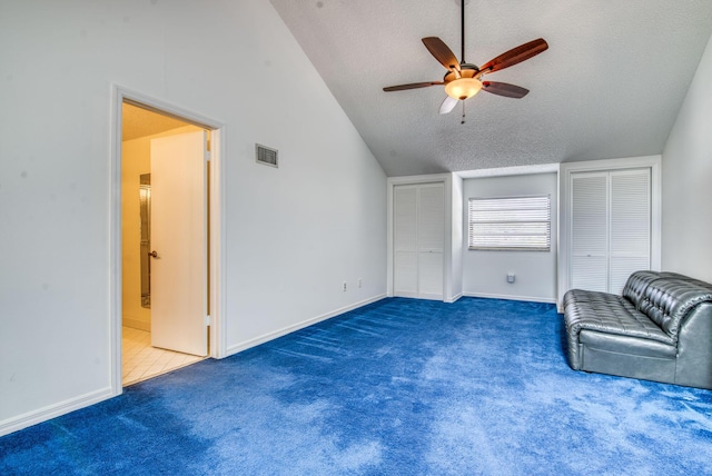 unfurnished room featuring a textured ceiling, dark carpet, ceiling fan, and lofted ceiling