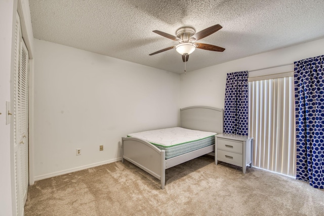 unfurnished bedroom with ceiling fan, a closet, light colored carpet, and a textured ceiling