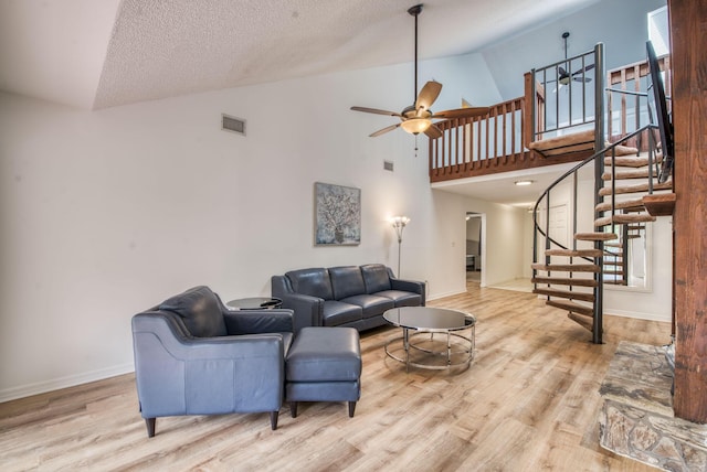 living room with ceiling fan, light hardwood / wood-style floors, a textured ceiling, and high vaulted ceiling