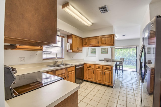 kitchen featuring kitchen peninsula, sink, light tile patterned floors, and appliances with stainless steel finishes