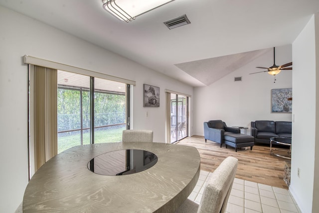 dining space with ceiling fan, light hardwood / wood-style floors, and vaulted ceiling