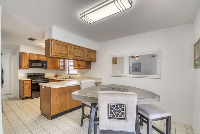 kitchen with kitchen peninsula, a kitchen bar, ceiling fan, sink, and electric range