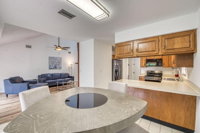 kitchen with ceiling fan, sink, kitchen peninsula, lofted ceiling, and appliances with stainless steel finishes