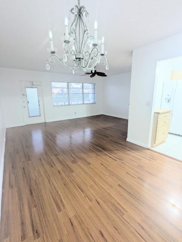 unfurnished dining area with a textured ceiling, an inviting chandelier, and hardwood / wood-style floors