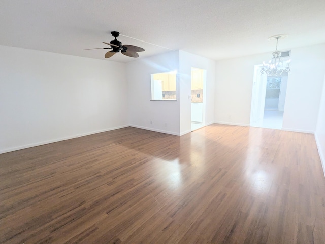 empty room with dark wood-type flooring and ceiling fan with notable chandelier