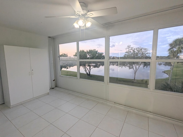 unfurnished sunroom with a water view and ceiling fan