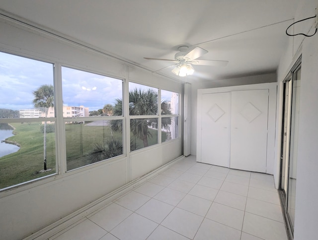 unfurnished bedroom featuring ceiling fan, light tile patterned floors, and a water view