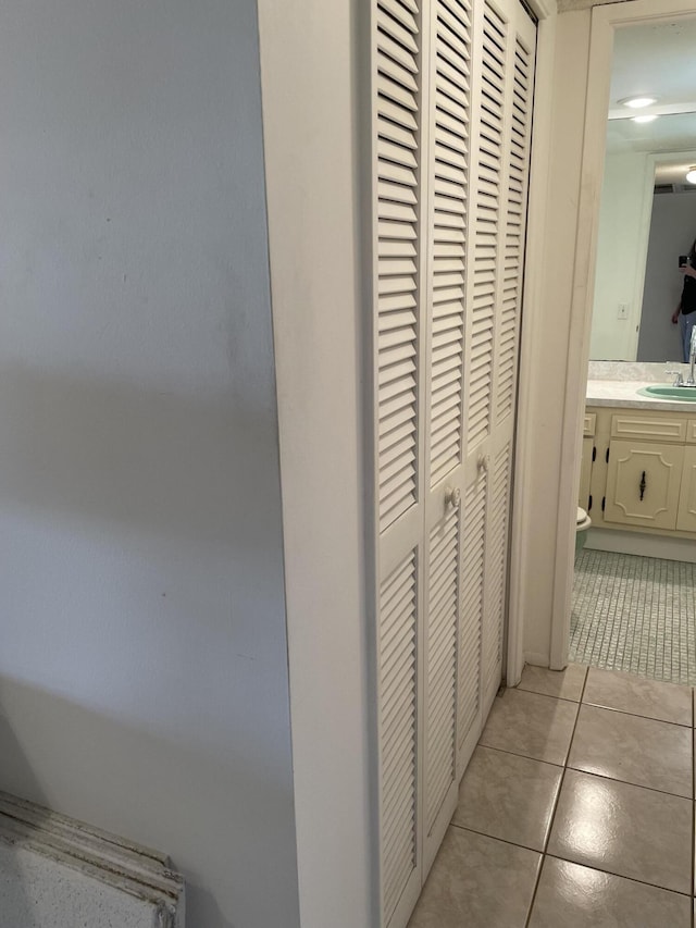 hall featuring sink and light tile patterned flooring