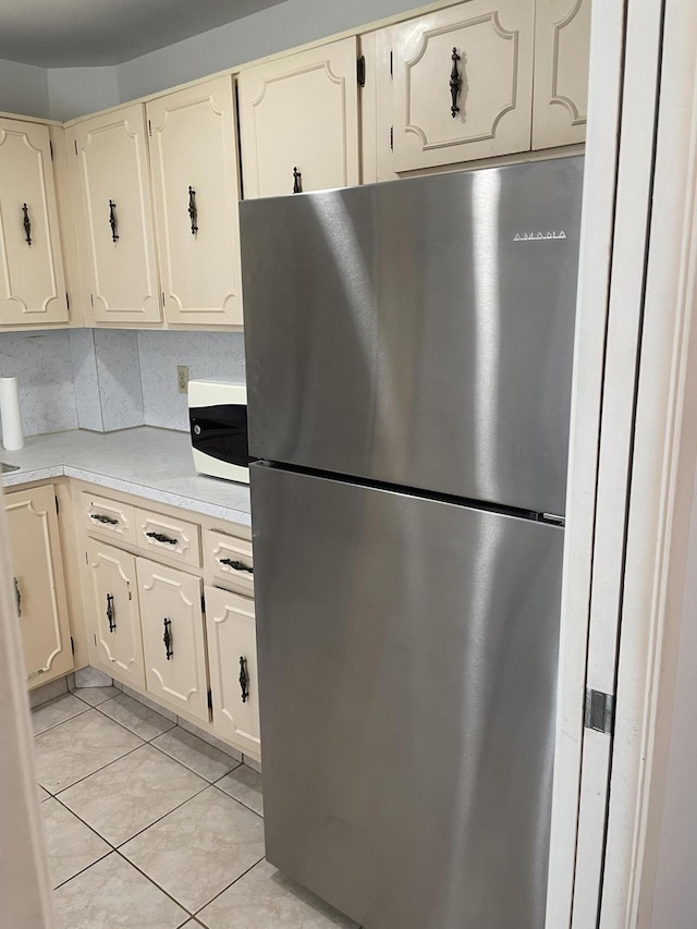 kitchen featuring stainless steel refrigerator, decorative backsplash, and light tile patterned flooring