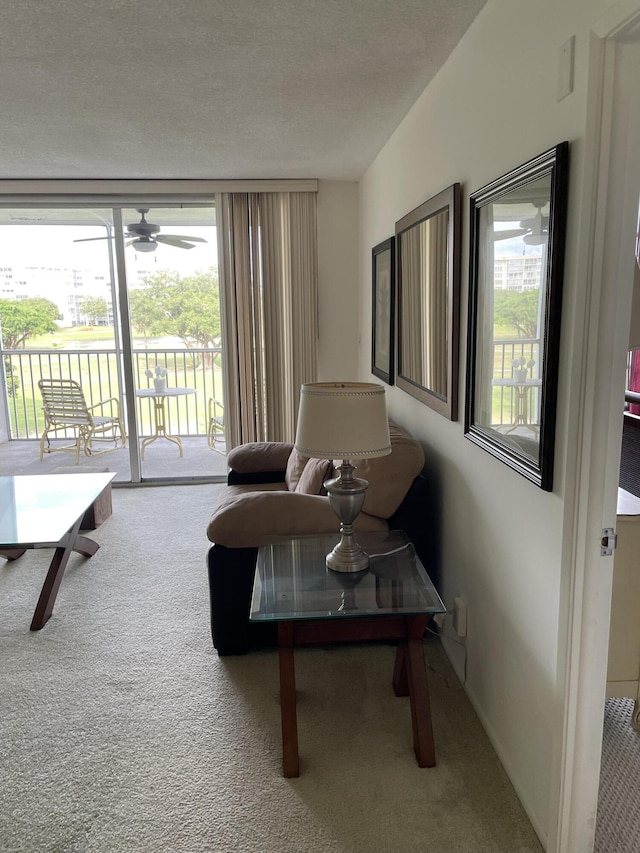 living room featuring carpet flooring, a textured ceiling, expansive windows, and ceiling fan