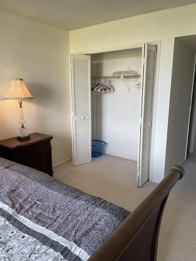 carpeted bedroom featuring a textured ceiling and a closet