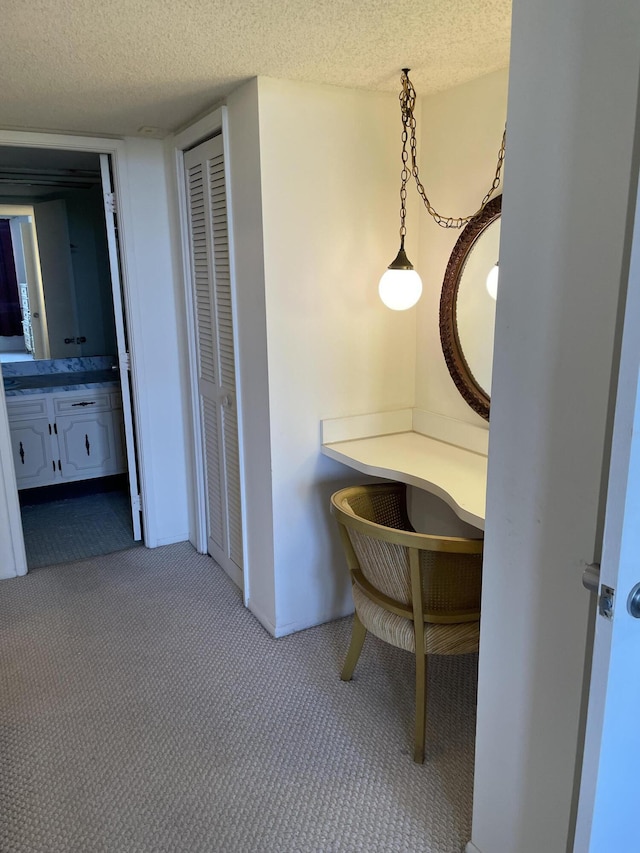 corridor with a textured ceiling and light carpet