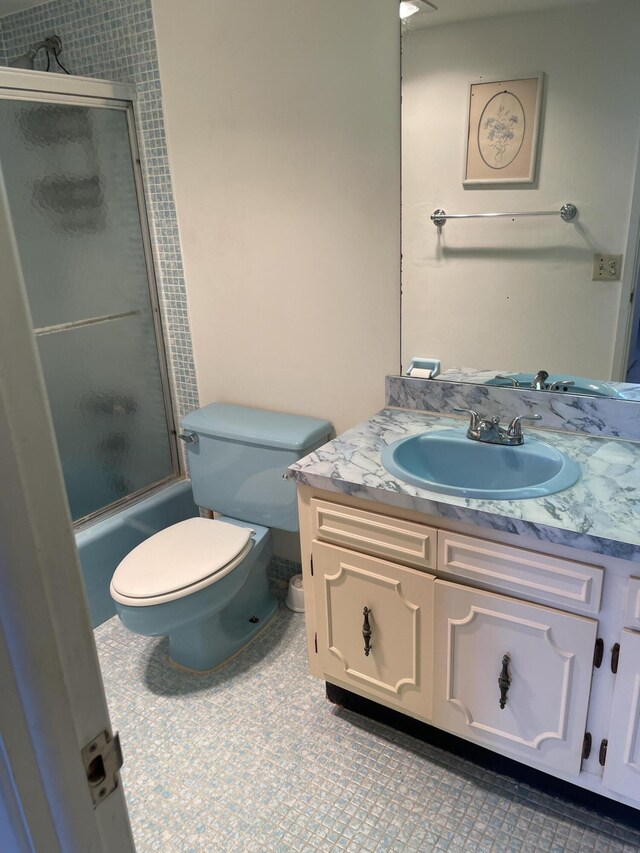 full bathroom featuring tile patterned flooring, vanity, combined bath / shower with glass door, and toilet