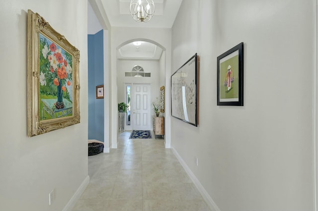 corridor with light tile patterned floors and a notable chandelier