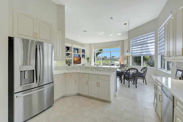 kitchen with kitchen peninsula, appliances with stainless steel finishes, light stone countertops, light tile patterned floors, and decorative light fixtures