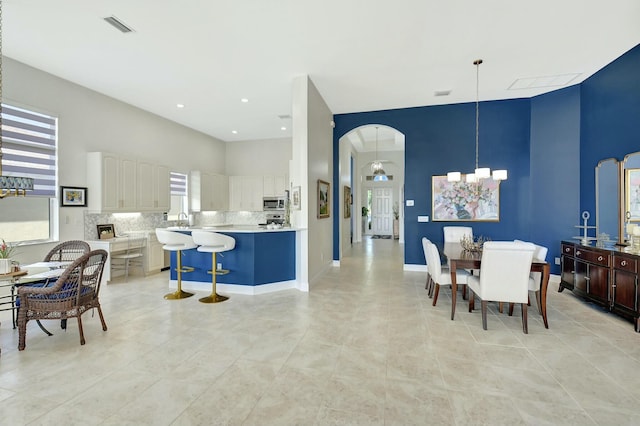 tiled dining room featuring a chandelier, a high ceiling, and sink