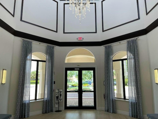 entryway with a notable chandelier, a healthy amount of sunlight, a high ceiling, and french doors