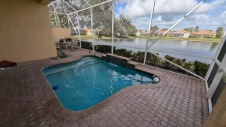 view of pool with a lanai, a patio area, and a water view