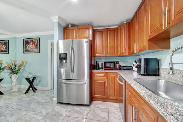 kitchen featuring stainless steel appliances, brown cabinets, a sink, and light stone countertops