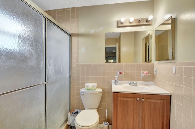 bathroom featuring vanity, toilet, a shower with shower door, and tile walls