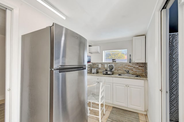 kitchen featuring sink, tasteful backsplash, stainless steel refrigerator, light stone countertops, and white cabinets