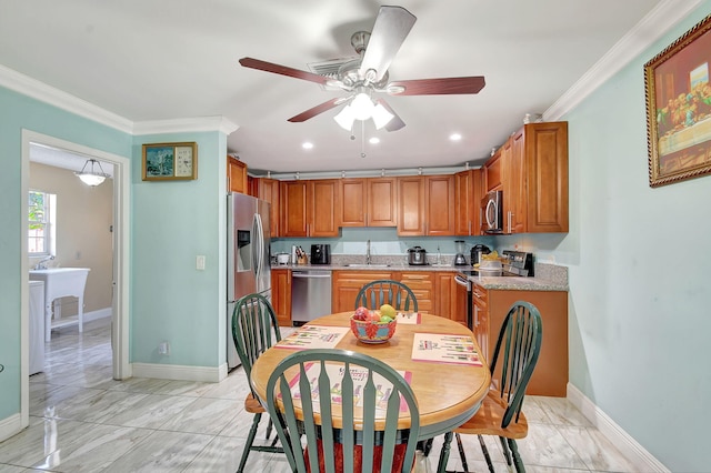 kitchen featuring brown cabinets, crown molding, stainless steel appliances, a sink, and baseboards