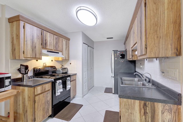 kitchen with sink, light tile patterned floors, stainless steel appliances, and a textured ceiling