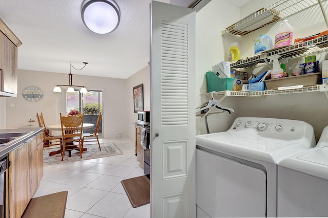 laundry room featuring light tile patterned floors, washer and dryer, a textured ceiling, and an inviting chandelier