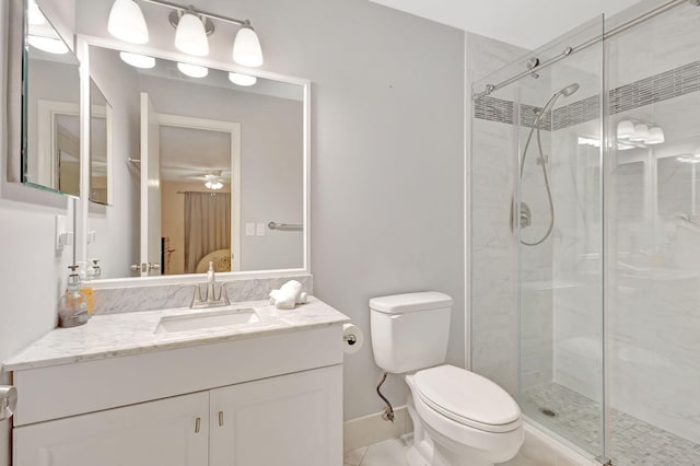 bathroom featuring ceiling fan, vanity, a shower with shower door, and toilet