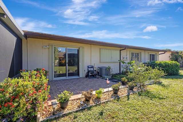 rear view of house with a lawn, cooling unit, and a patio area