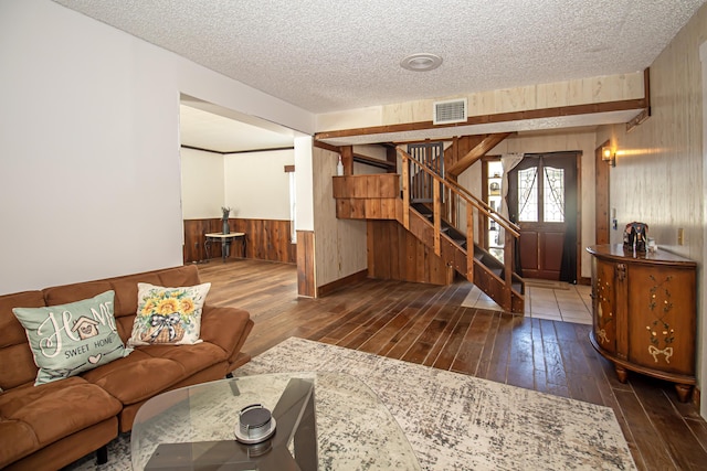 living room with wooden walls, dark hardwood / wood-style flooring, and a textured ceiling