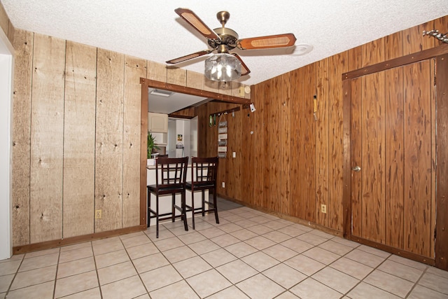 unfurnished dining area with a textured ceiling, ceiling fan, and wooden walls