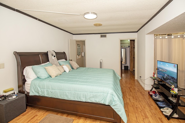 bedroom featuring crown molding, a textured ceiling, and light hardwood / wood-style flooring