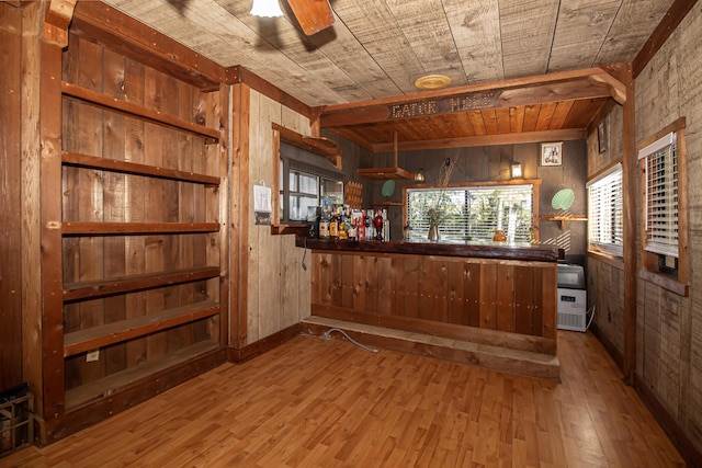 bar featuring light wood-type flooring, ceiling fan, wood walls, and wood ceiling