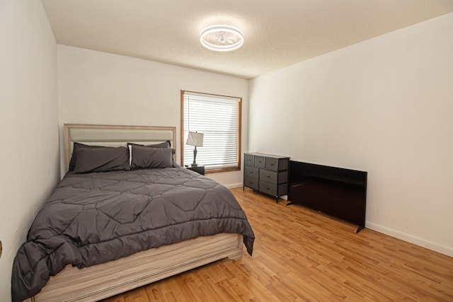 bedroom with a textured ceiling and light hardwood / wood-style flooring