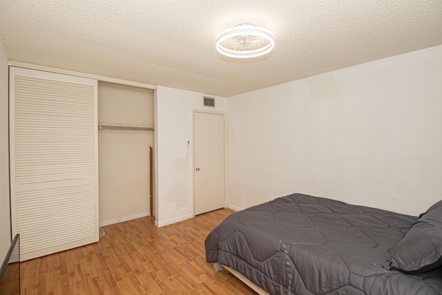 bedroom featuring light wood-type flooring, a textured ceiling, and a closet