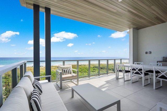 balcony featuring a view of the beach, a water view, and an outdoor hangout area