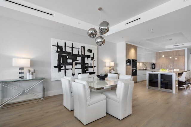 dining space featuring light wood-type flooring and a tray ceiling