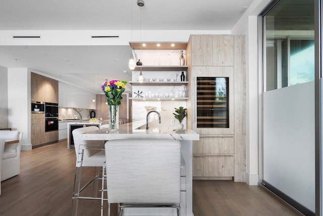 kitchen featuring wine cooler, pendant lighting, a center island with sink, decorative backsplash, and a breakfast bar area