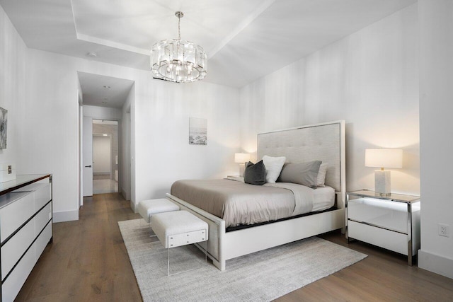 bedroom with dark hardwood / wood-style floors, a raised ceiling, and a chandelier