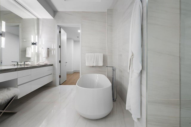 bathroom with tile walls, vanity, and a bathing tub