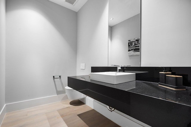 bathroom featuring toilet, vanity, and wood-type flooring