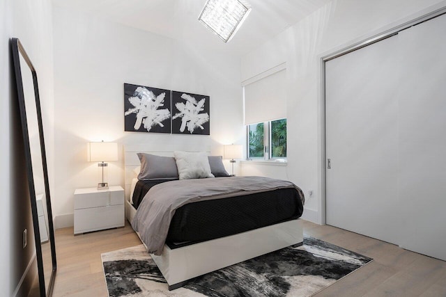 bedroom with lofted ceiling, light wood-type flooring, and a closet