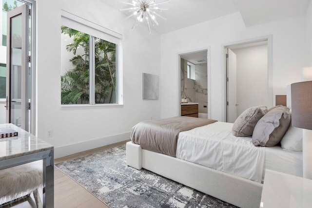 bedroom featuring a notable chandelier, connected bathroom, and light hardwood / wood-style floors